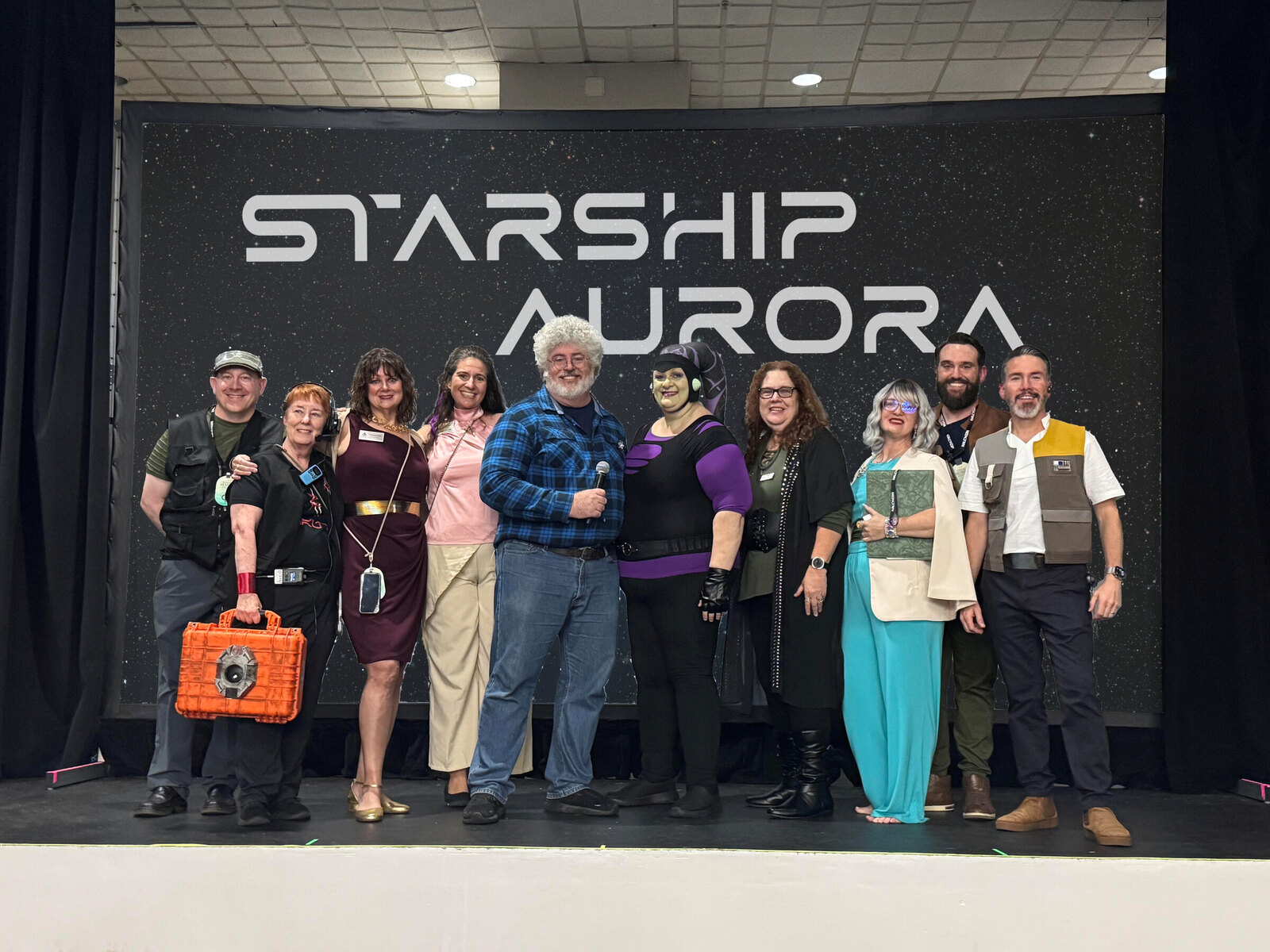 The crew of the Starship Aurora onstage under the STARSHIP AURORA logo at Halcy-Con 3
